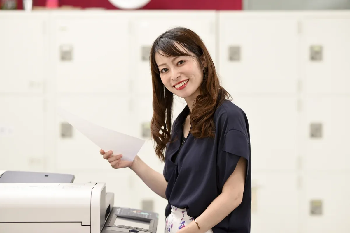 プリンターの前で印刷した書類を確認する女性
