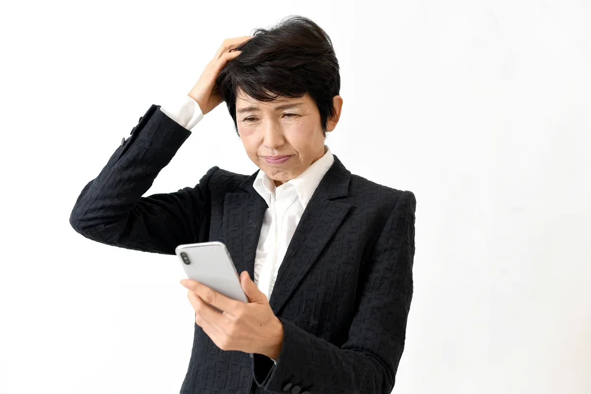 スマートフォンの操作に困る中年女性